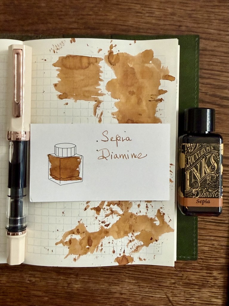 A fountain pen and an ink bottle labeled 'Sepia Diamine' placed on a notebook with ink splatters and a hand-drawn illustration of the ink bottle.